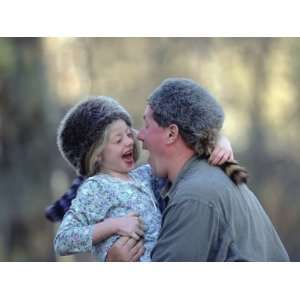  A Father and His Daughter Laugh Together While Wearing Coonskin 